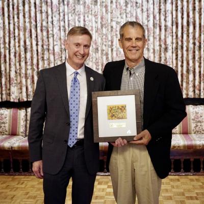 CSS CEO Bob Stokes stands with Jim Pianalto, who is holding a framed piece of art.