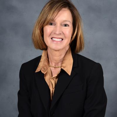 Professional photo of Leslie Stoyer in a black blazer with a gold collared shirt