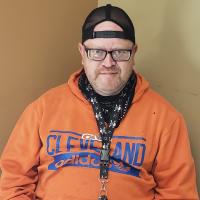 Head and shoulders photo of Jay Robinson in an orange sweatshirt and backwards black baseball hat