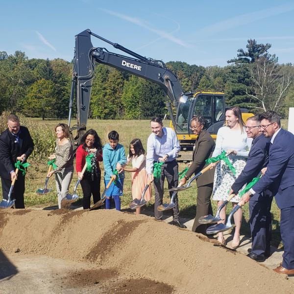 Speakers from the center's groundbreaking line up with shovels in hand, pitching dirt at the groundbreaking.